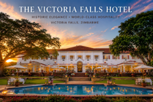 Elegant exterior of The Victoria Falls Hotel in Zimbabwe, featuring beautifully landscaped gardens, a sparkling pool, outdoor dining areas, and classic colonial architecture near the world-famous Victoria Falls.