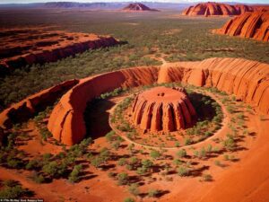 Uluru (Ayers Rock) rising from Australia’s red desert at sunrise, showcasing sacred sandstone formations, glowing colors, and the vast natural beauty of the Australian Outback.