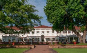 Victoria Falls Safari, Hiking, and Drone Views 3 Victoria Falls hotel nestled among trees, with a stone wall in front and lush greenery surrounding the property.