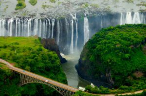 Victoria Falls Safari, Hiking, and Drone Views 4 Bird’s-eye view of Victoria Falls with a bridge spanning the gorge, surrounded by dense rainforest and cascading water.