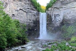Waterfalls with steep rock walls with trees and vegetation on a sunny day.