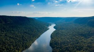 Aerial view of a winding river flowing through a broad forested Appalachian valley surrounded by steep mountain ridges.