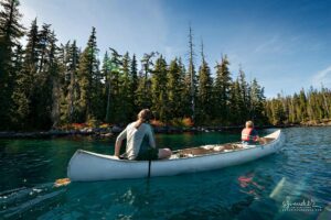 Tahkenitch Lake Oregon canoeing adventure with waterfall, forest scenery, wildlife including deer and birds, and a peaceful river setting perfect for outdoor exploration.