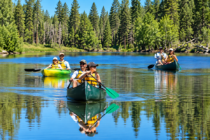 Bryce Canyon Utah Vacation 4 Three groups of paddlers canoeing across a calm forest lake surrounded by tall evergreen trees on a sunny day.