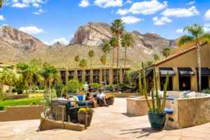 Joshua Tree National Park Calif. 8 Guests relaxing at a luxury desert resort near Joshua Tree National Park with palm trees, mountain views, outdoor lounge seating, and a sunny California sky.