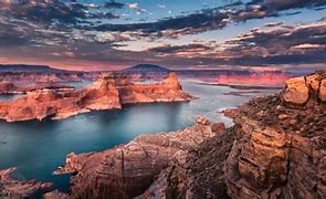 Canyon with steep walls with a lake and partly cloudy sky at sunset.