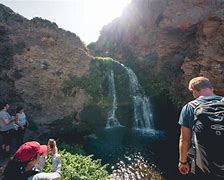 two people standing next to waterfall