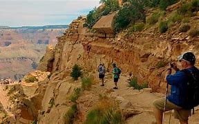 South Kaibab Trail Canyon Vacation 8 People backpack hiking on a trail in a canyon with steep cliffs