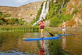 Shoshone Falls Idaho Vacation 7 Two people paddleboarding at a lake with a waterfalls and steep cliffs