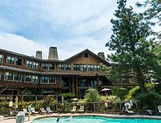 Breathtaking Oregon: How to Vacation in the Cascade Range 7 People at a pool with lawn chairs and umbrellas at a hotel with partly cloudy sky.