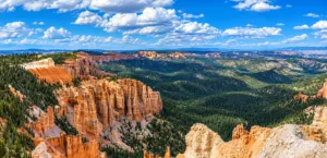 Valley of the Gods Utah: Camping, Hiking & Scenic Drive Guide 1 Panoramic view of colorful hoodoos, rugged canyon cliffs, and forested valleys beneath a bright blue Utah sky.