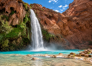 Havasu Falls cascading from red canyon cliffs into a brilliant turquoise pool in Arizona.