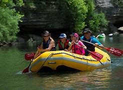 people in a raft floating down a river in the woods