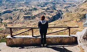 Explore Colca Canyon, Peru: Ultimate Adventure & Vacation Guide 5 Person standing looking at a canyon with a railing in front>