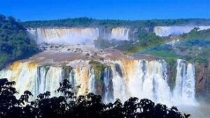 Waterfalls with steep cliffs in a rainforest on a blue-sky day.