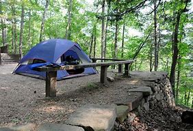 tent in the woods with railing and stone walls in the woods.