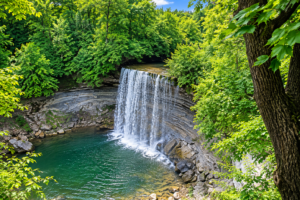 Bridal Veil Falls Utah: Hiking, Waterfalls & Outdoor Adventures 4 Scenic waterfall cascading over layered rock into a clear pool surrounded by dense green forest near Bridal Veil Falls, Utah.