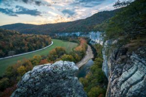 steep cliffs in a forest with a river that flows through on a partly cloudy day.