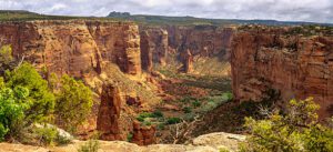 Canyon with steep cliffs and rock structures with trees on a cloudy day.