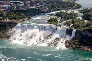 Waterfalls with many building and steep cliffs and trees.