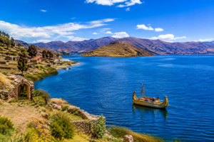 Lake Titicaca with traditional reed boat, blue water, and Andean mountains near Cusco, Peru