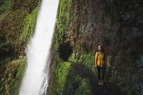 woman trail hiking along a path near a waterfsall