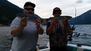 two men holding fish from the day of fishing on a lake