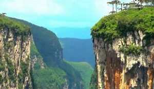 tall steep cliffs at a rainforest with lots of vegetation on a partly cloudy day.