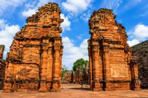 Iguazu Falls Photography Tours 6 Historic Jesuit Mission ruins in San Ignacio, Argentina, featuring beautifully preserved red sandstone archways and intricate colonial architecture beneath a bright blue sky.