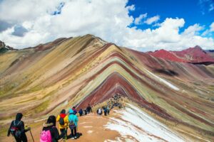 Exploring Cusco, Peru: Gateway to Ancient Ruins and Adventure 6 Hikers exploring the colorful striped mountains near Cusco, Peru, with vibrant red, orange, and green peaks under a clear sky.