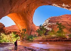 hiker standing in a large cave wearing backpack with a large puddle of water
