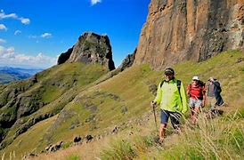 Tugela Falls, South Africa Tour 4 People trail hiking with backpacks at a canyon with steep walls and vegetation.