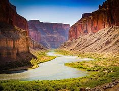 canyon with steep cliffs with a river retuning through the center with vegetation