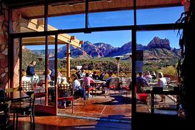 Sedona Canyon Hiking And Vacation Tours 6 people sitting at tables at a restaurant with tables and chairs and mountains in the background