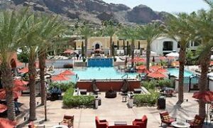 Grand Canyon Luxury Hotel with pool and chairs and Palm trees and mountains in the basckground