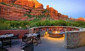 Sedona Canyon Hiking And Vacation Tours 7 tables and chairs and a fire burning at a restaurant with steep canyon walls and trees in the background