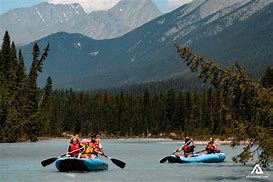 Rocky Mountain National Park Camping & Hiking 3 Several people rafting on two rafts on a lake with a forest and large mountains in the background.