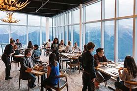 Rocky Mountain National Park Camping & Hiking 7 People sitting in chairs at tables with food with large windows at a restaurant.
