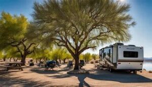 Camper with trees and grill and other structures on a blue-sky day.