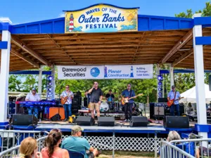 Pea Island Beach, NC, Camping & Hiking Tours 6 Live outdoor music performance near Pea Island Beach, North Carolina, with musicians performing on a festival stage as visitors watch from the audience.