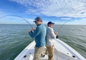 Two people fishing from a small boat on the ocean, with calm waters and a clear horizon.
