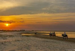Beach at sunset with people walking on the sand,