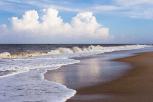 Figure Eight Island Beach, NC, Camping & Hiking Tours 1 Sandy beach with gentle ocean waves rolling onto the shore.