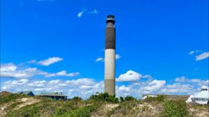 Lighthouse at Oak Island, North Carolina, near the ocean with sandy shore.