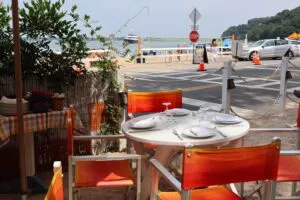 Figure Eight Island Beach, NC, Camping & Hiking Tours 7 Beachside dining table with orange chairs, place settings, and ocean views near a lively sandy beach.