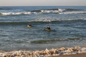 Isle of Palms, South Carolina: Beach Camping Getaways, Coastal Adventures & Scenic Escapes 6 Two kayakers paddling yellow kayaks through rolling ocean waves near a sandy beach, with white surf breaking along the shoreline and the open Atlantic Ocean stretching into the distance.