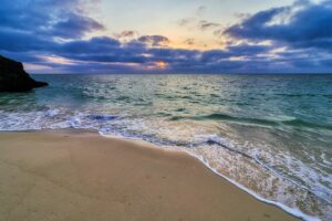 A sandy beach at sunset along the ocean at Crystal Coast Beach, NC.
