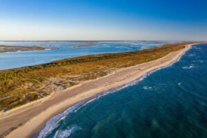 Long stretch of land with sandy beaches and the ocean on both sides.