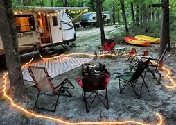camper and chairs with lights on the camper with other camping equipment.