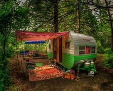 camper in the woods with a rug on the floor in front of a trailer and a tsable with trees